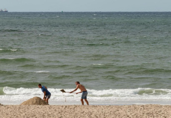 Twee personen graven in het zand op het strand bij Resort Beach Houses Julianadorp 1, Nederland.