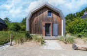 Casa de vacaciones moderna «Waterland para seis personas» en Países Bajos con fachada de madera y sendero de arena.