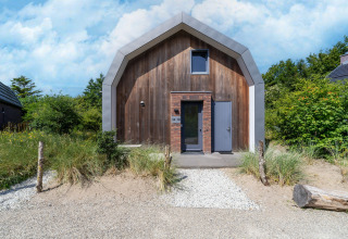 Casa de vacaciones moderna «Waterland para seis personas» en Países Bajos con fachada de madera y sendero de arena.
