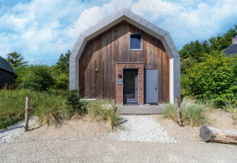 Maison de vacances moderne « Waterland pour six personnes » aux Pays-Bas avec façade en bois et allée sableuse.