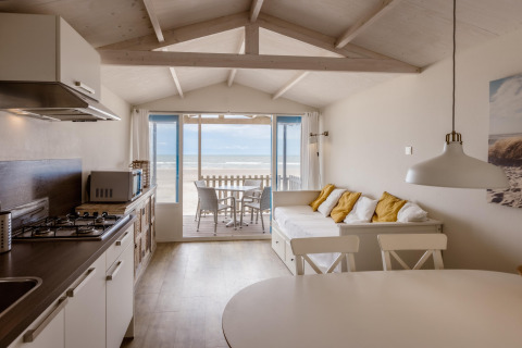 Bright beach house with open kitchen, sofa with cushions, and terrace overlooking the sea view.