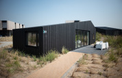 Modernes, schwarzes Strandhaus bei Sea Lodges Zandvoort in den Niederlanden, umgeben von SanddĂĽnen.