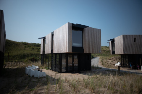 Casa de playa moderna en Sea Lodges Zandvoort con fachada de madera y ventanas grandes junto a dunas.