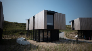 Casa de playa moderna en Sea Lodges Zandvoort con fachada de madera y ventanas grandes junto a dunas.