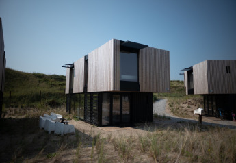 Modernes Strandhaus bei Sea Lodges Zandvoort mit Holzfassade und groĂźen Fenstern in DĂĽnenlandschaft.