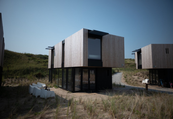 Casa de playa moderna en Sea Lodges Zandvoort con fachada de madera y ventanas grandes junto a dunas.
