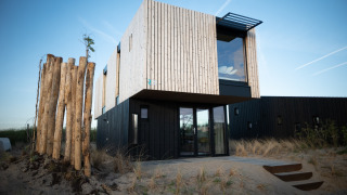 Casa de playa moderna Sea Lodges Zandvoort 6 con fachada de madera y vidrio entre dunas bajo cielo azul