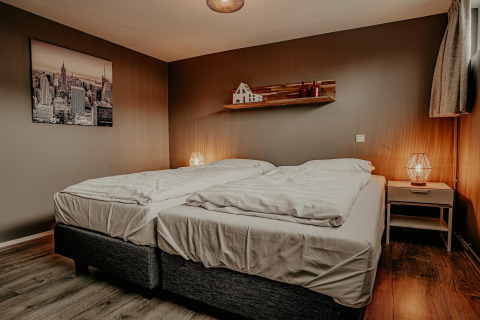 Moderne slaapkamer met twee enkele bedden op woonboot Waterpark de Meerparel 5 in Nederland, bruin decor.
