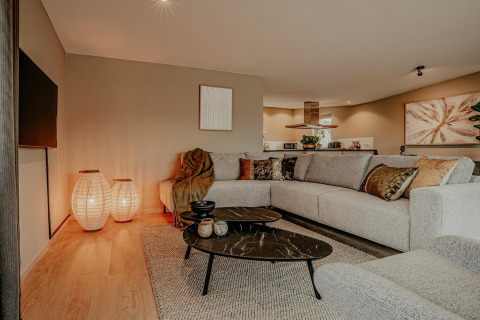 Stilfuld stue på husbåd Waterpark de Meerparel 5 i Holland med moderne sofa og varme lamper.