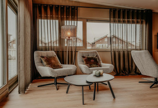 Moderne woonkamer op een woonboot met gezellige zetels, salontafels en grote ramen in Waterpark de Meerparel 5.