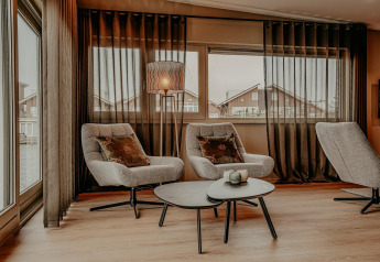 Modern living area on a houseboat with cozy armchairs, coffee tables, and large windows in Waterpark de Meerparel 5.