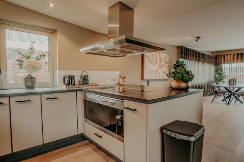 Moderne keuken op woonboot Waterpark de Meerparel 5 in Nederland, met een eetruimte en fornuis.