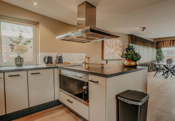 Modern kitchen on houseboat Waterpark de Meerparel 5 in the Netherlands, with stove and dining area.
