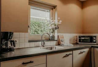 Cocina moderna con fregadero, cafetera, horno y jarrón de flores en la casa flotante de Meerparel 5.
