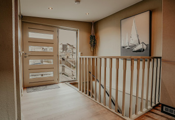 Entryway of houseboat Waterpark «de Meerparel 5» in the Netherlands featuring modern stairs and decor.