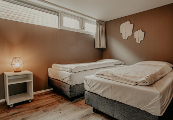 Modern bedroom with two single beds, a nightstand lamp, and windows on houseboat Waterpark de Meerparel 5.