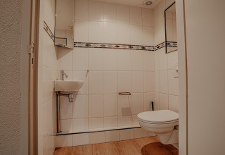Baño moderno en una casa flotante de Waterpark de Meerparel 5 con inodoro de pared y lavabo pequeño.