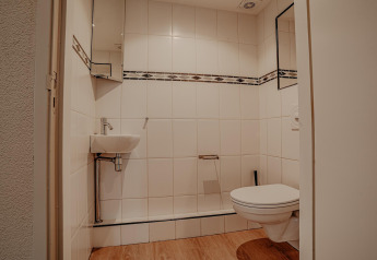 Modern houseboat bathroom at Waterpark de Meerparel 5 in the Netherlands with wall toilet and sink.