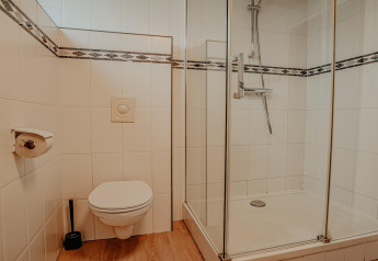 Bathroom with wall-mounted toilet, glass shower enclosure, and wood-look floor in a Dutch houseboat.
