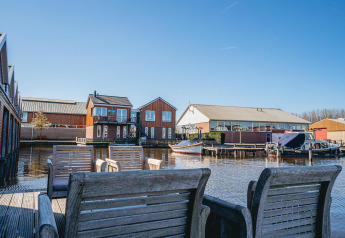 View from a wooden terrace with chairs towards houseboats and boats at Waterpark de Meerparel 5 in the Netherlands.