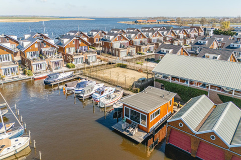 Luchtfoto van woonboten en waterwoningen in Waterpark de Meerparel 5, Nederland, met boten aan de steiger.
