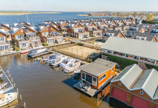 Luchtfoto van woonboten en waterwoningen in Waterpark de Meerparel 5, Nederland, met boten aan de steiger.