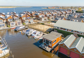 Aerial view of houseboats and waterfront homes at Waterpark de Meerparel 5, Netherlands, with docked boats.