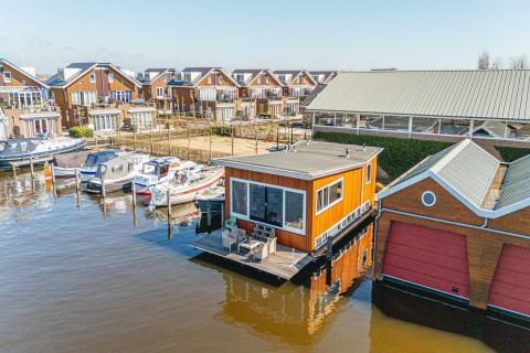 Hausboot im Waterpark de Meerparel 5 in den Niederlanden, umgeben von Booten und modernen Häusern.