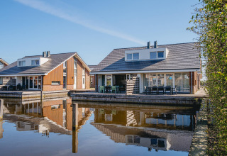 Zwei moderne Glamping-Unterkünfte am Wasser mit großzügigen Terrassen und Spiegelung im ruhigen See.
