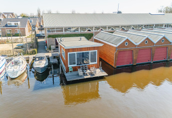 Houseboat Waterpark de Meerparel 5 in the Netherlands, featuring terrace, boats, boat garages over the water.