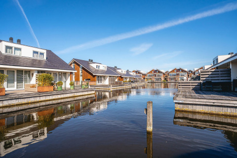Moderne Ferienhäuser am Wasser auf einem Glamping-Gelände mit Holzterrassen und klarem Himmel.