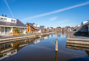Waterfront glamping cabins with private decks, calm water, and blue sky in a tranquil holiday setting.