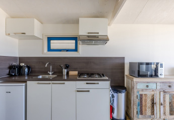 Moderne keuken in strandhuis met fornuis, magnetron, koelkast en koffiezetapparaten op het aanrecht.