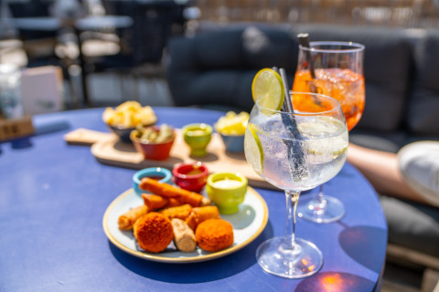 Delicious snacks and colorful cocktails served on a blue table in the relaxed atmosphere of a beach house.
