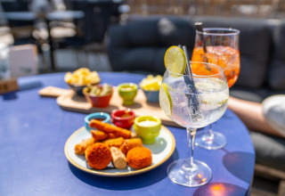 Delicious snacks and colorful cocktails served on a blue table in the relaxed atmosphere of a beach house.