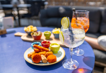 Heerlijke hapjes en kleurrijke drankjes geserveerd op een blauwe tafel in een sfeervol strandhuis.