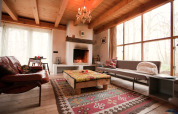 Cozy living area in De Schone Leij cabin, Netherlands, featuring fireplace, wooden beams, and large windows.