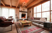 Cozy living area in De Schone Leij cabin, Netherlands, featuring fireplace, wooden beams, and large windows.