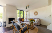 Salon avec mobilier moderne, cheminée, grandes fenêtres et tournesols à Waterland Holiday home, Pays-Bas.