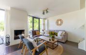 Living room with modern furniture, fireplace, large windows and sunflowers at Holiday home Waterland, NL.