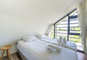 Lyst soveværelse i Holiday home Waterland for six Person i Holland, med dobbeltseng og store vinduer.