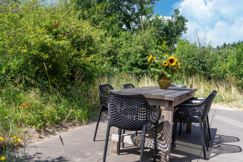 Tavolo da esterno con sei sedie nere e un vaso di girasoli, immerso nel verde nei Paesi Bassi.