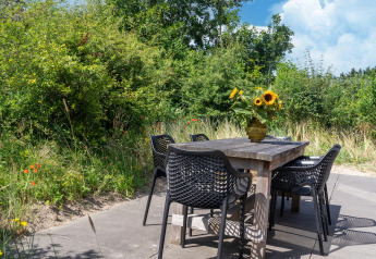 Gartentisch mit sechs schwarzen Stühlen und Sonnenblumen in der Vase, umgeben von Natur in den Niederlanden.