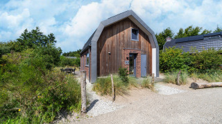 Vakantiehuis Waterland voor zes personen met moderne houten look, gelegen langs een grindpad in de natuur.