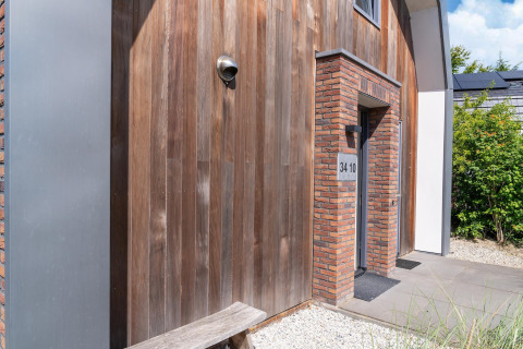 Entrada a la casa de vacaciones Waterland para seis personas en Países Bajos, con fachada de madera y ladrillo.