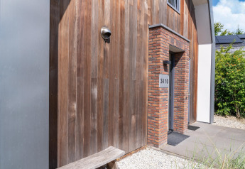 Entrada a la casa de vacaciones Waterland para seis personas en Países Bajos, con fachada de madera y ladrillo.
