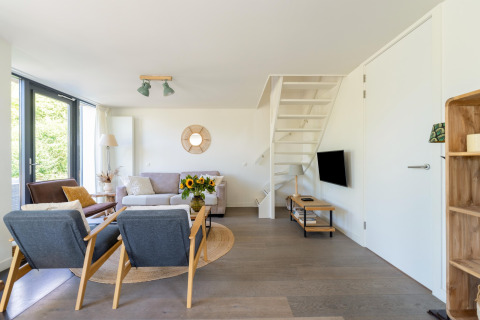 Lyst og moderne opholdsstue i feriehuset 'Waterland for seks personer' i Holland, med stilfuld indretning.