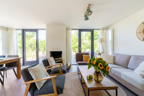 Helles, modernes Wohnzimmer im Ferienhaus Waterland für sechs Personen in den Niederlanden mit Sonnenblumen.