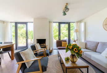 Lichte, moderne living in vakantiehuis Waterland voor zes personen in Nederland met vrolijke zonnebloemen.