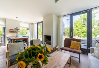 Helles Wohnzimmer im Holiday Home Waterland für sechs Personen mit großen Fenstern und Sonnenblumen.